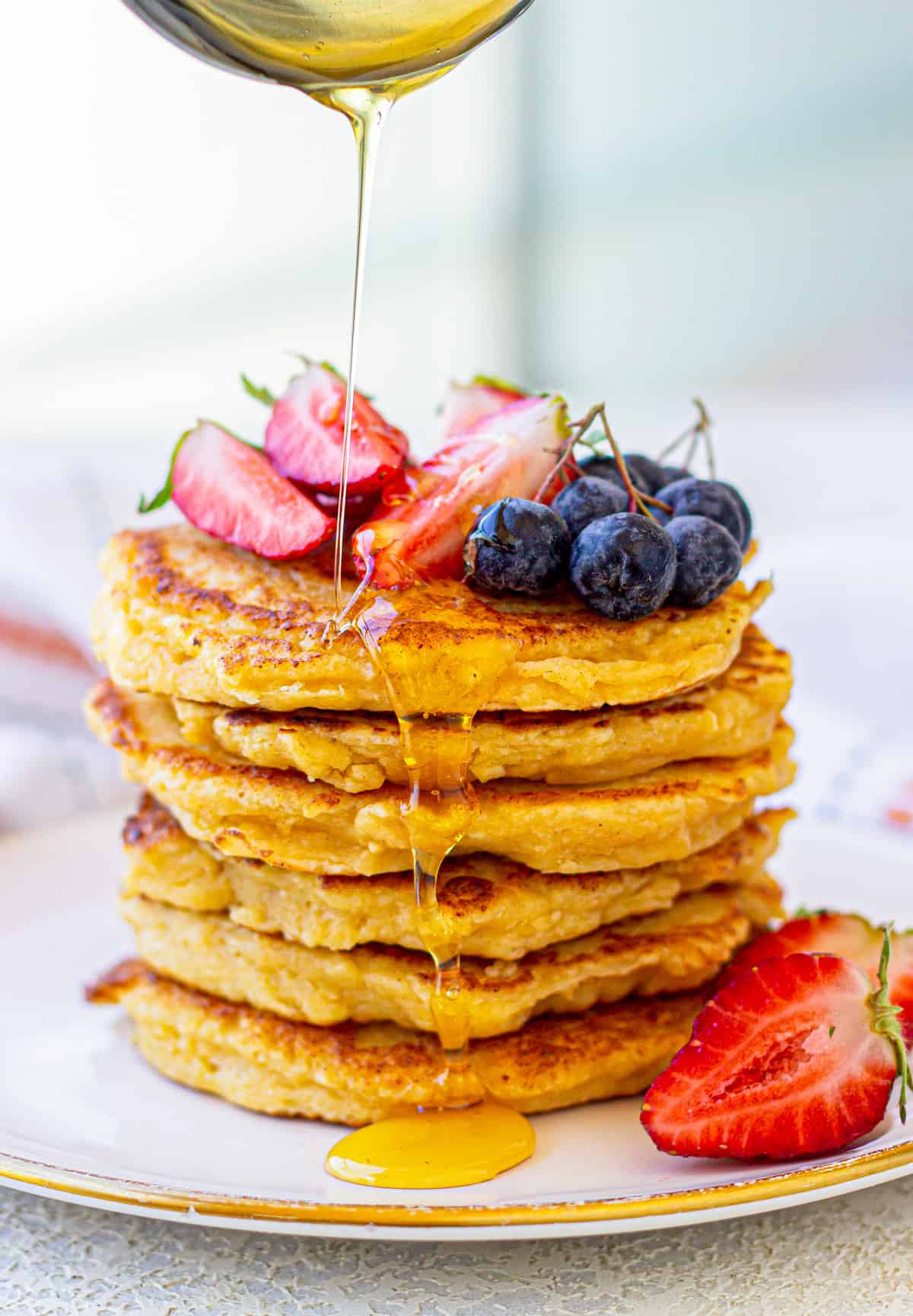 Stack of cottage cheese pancakes, with honey and berries.