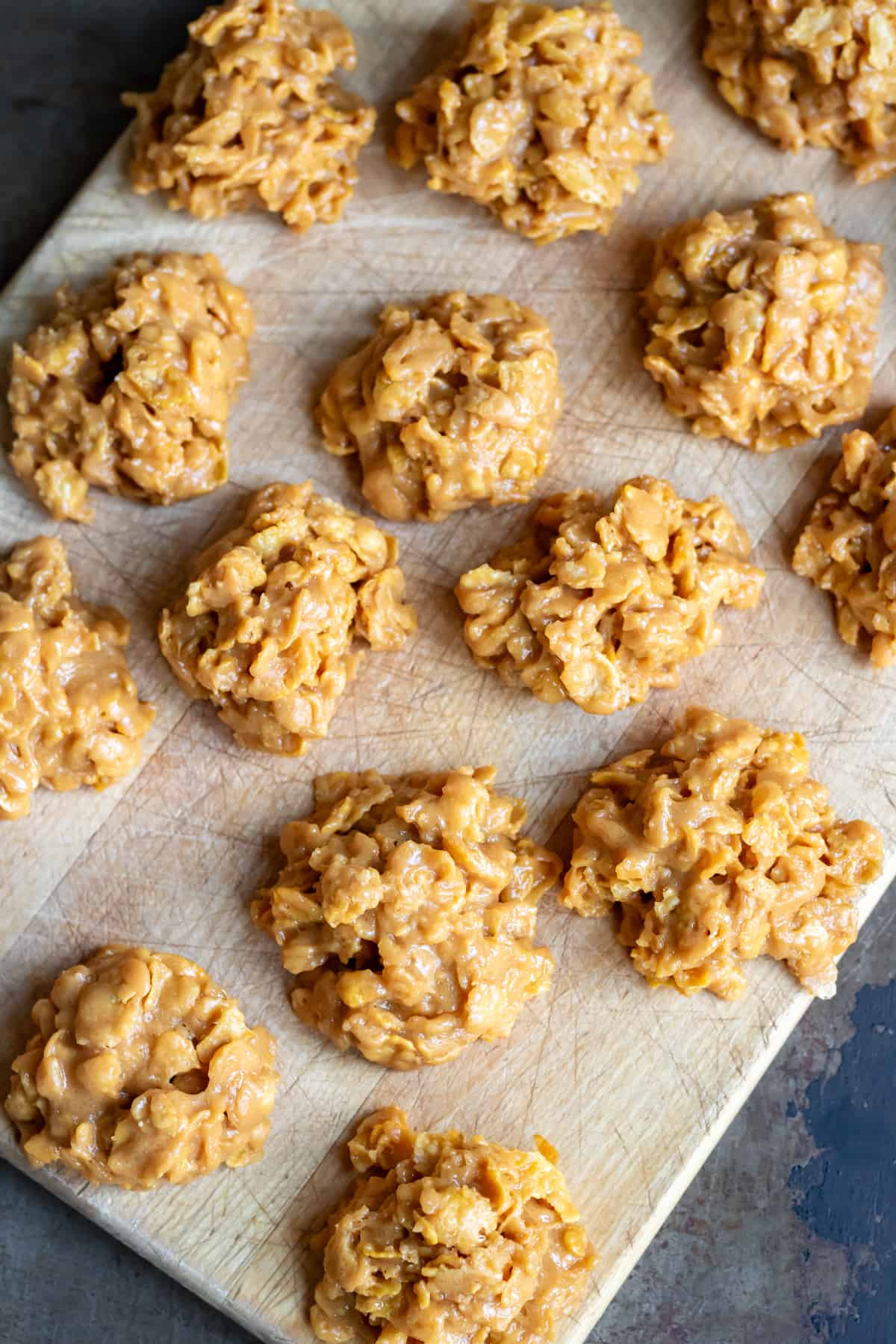 Rows of cornflake cookies on a wooden board.