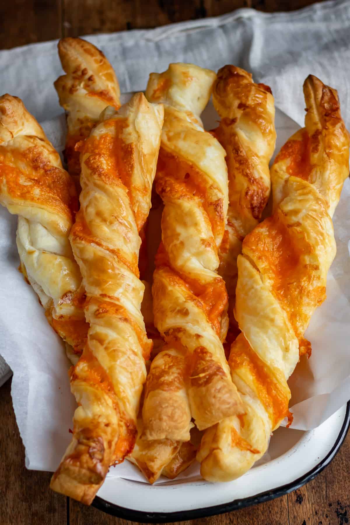 Close up of a pile of garlic cheese twists made with puff pastry.