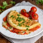 Folded pizza omelet (filled with pepperoni, pizza sauce and mozzarella) on a plate.