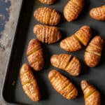 A baking sheet with baked fingerling hassleback potatoes.
