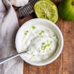 Bowl of lime crema next to zested limes.