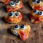 Close up of mini folded pastry pizzas with olive 'eyes' to look like monsters.