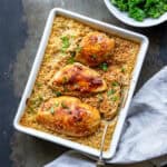 A table with a baking dish of Korean baked chicken breasts and rice, with a bowl of steamed kale next to it.