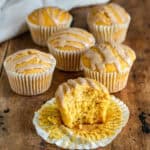 A pumpkin muffin with a bite out, in front of more pumpkin muffins.