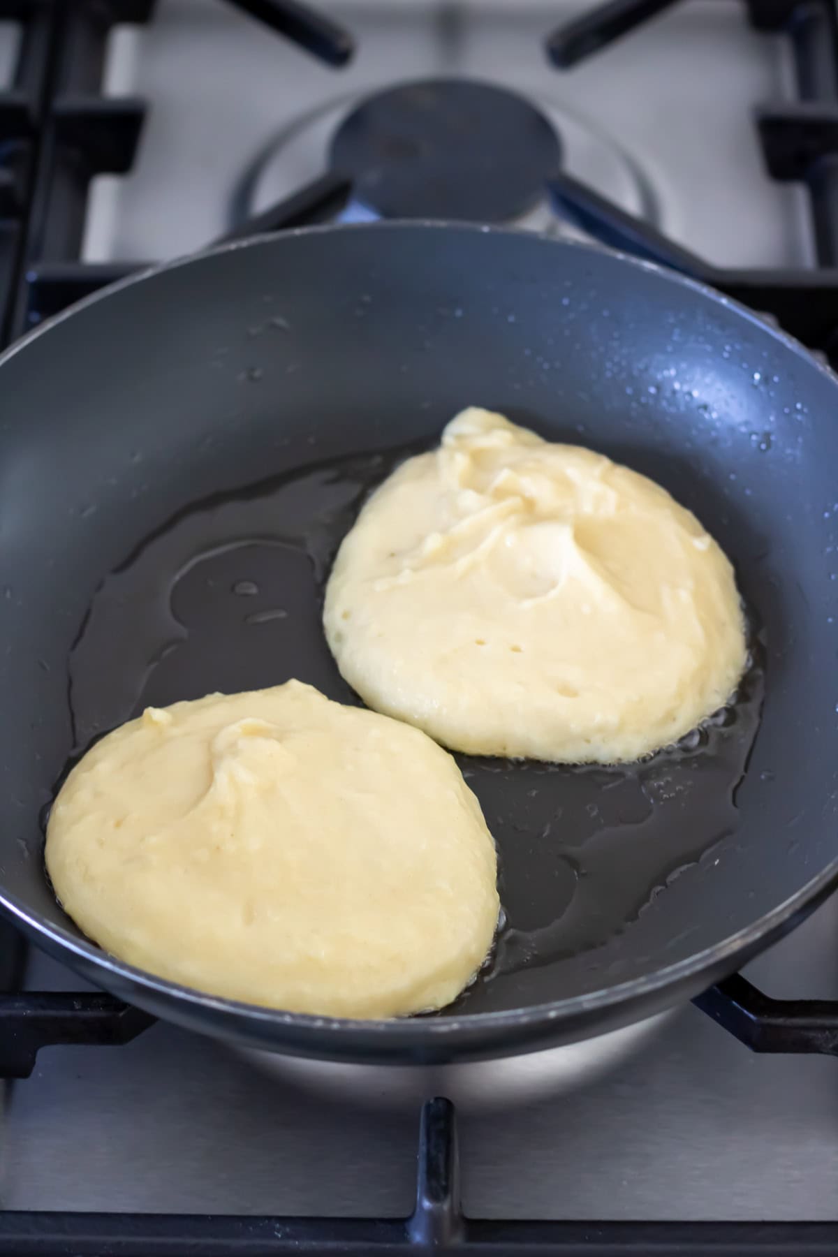 Adding mashed potato batter to the frying pan.