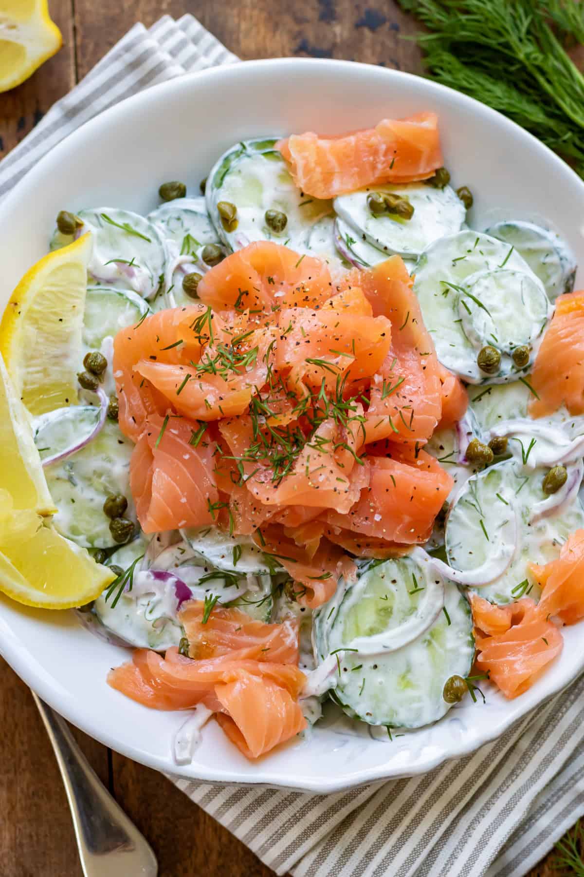 A bowl of smoked salmon cucumber salad on a table.
