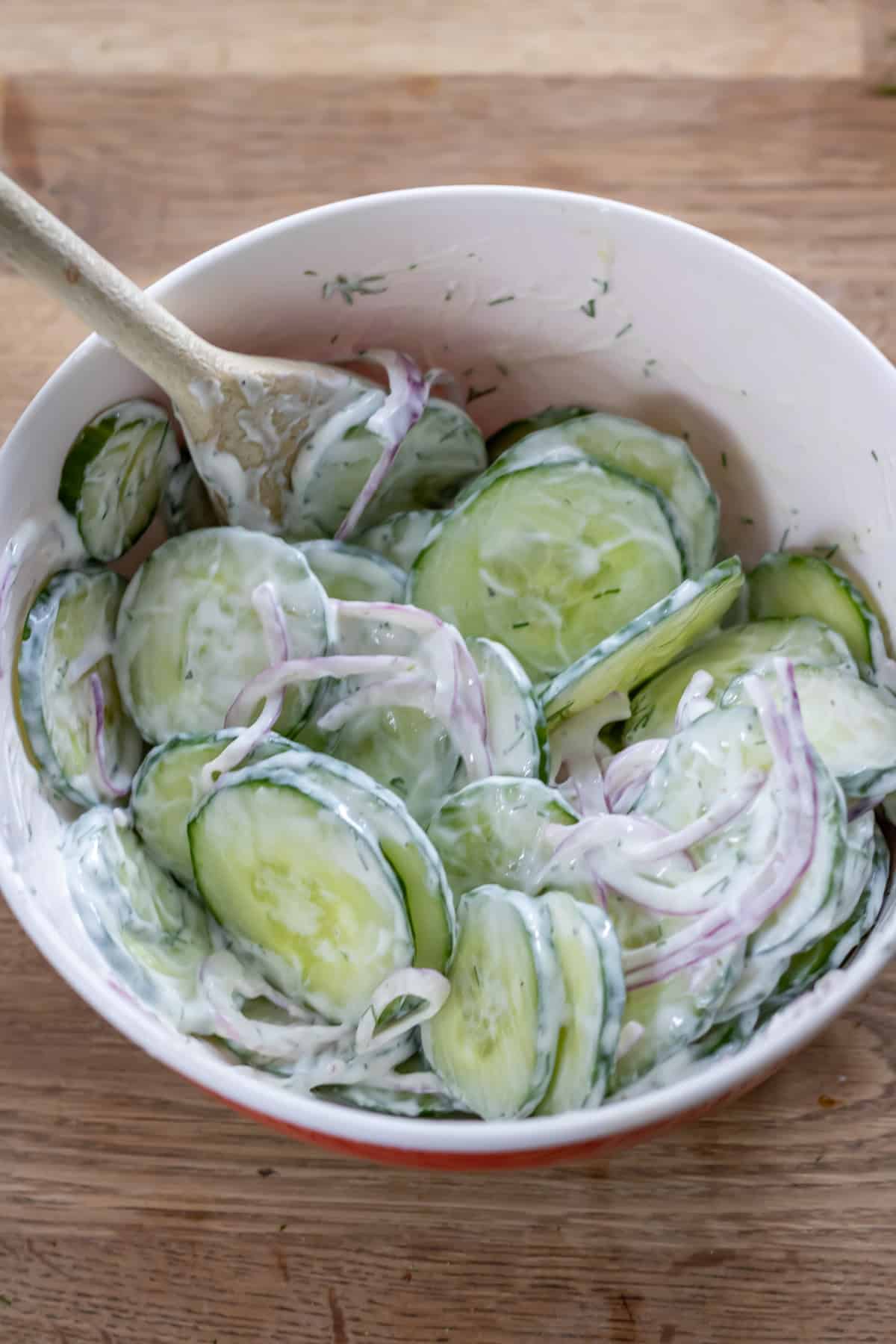 Mixing the dressing into the cucumber.
