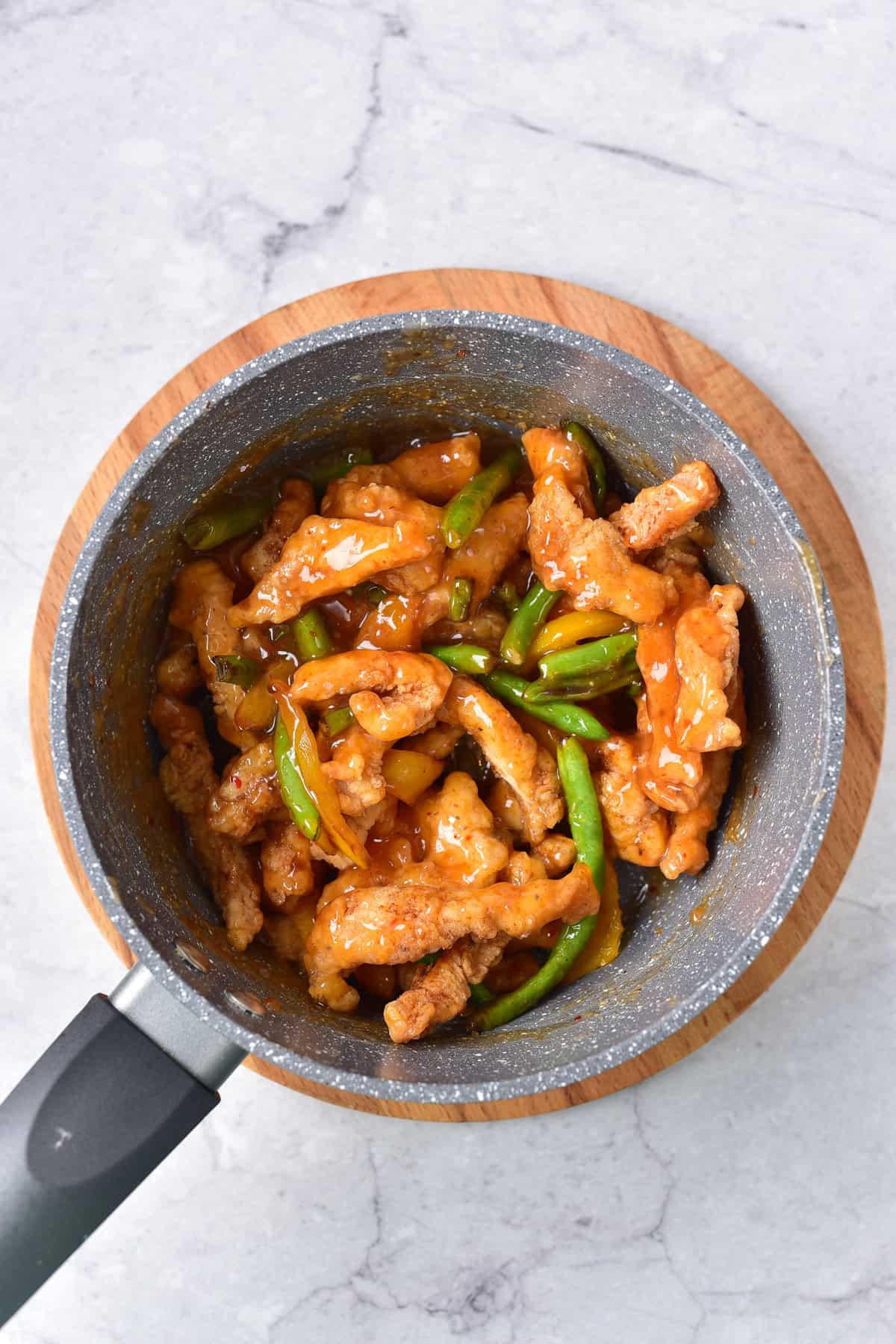Tossing the fried chicken strips and sauteed vegetables in the honey sesame sauce.
