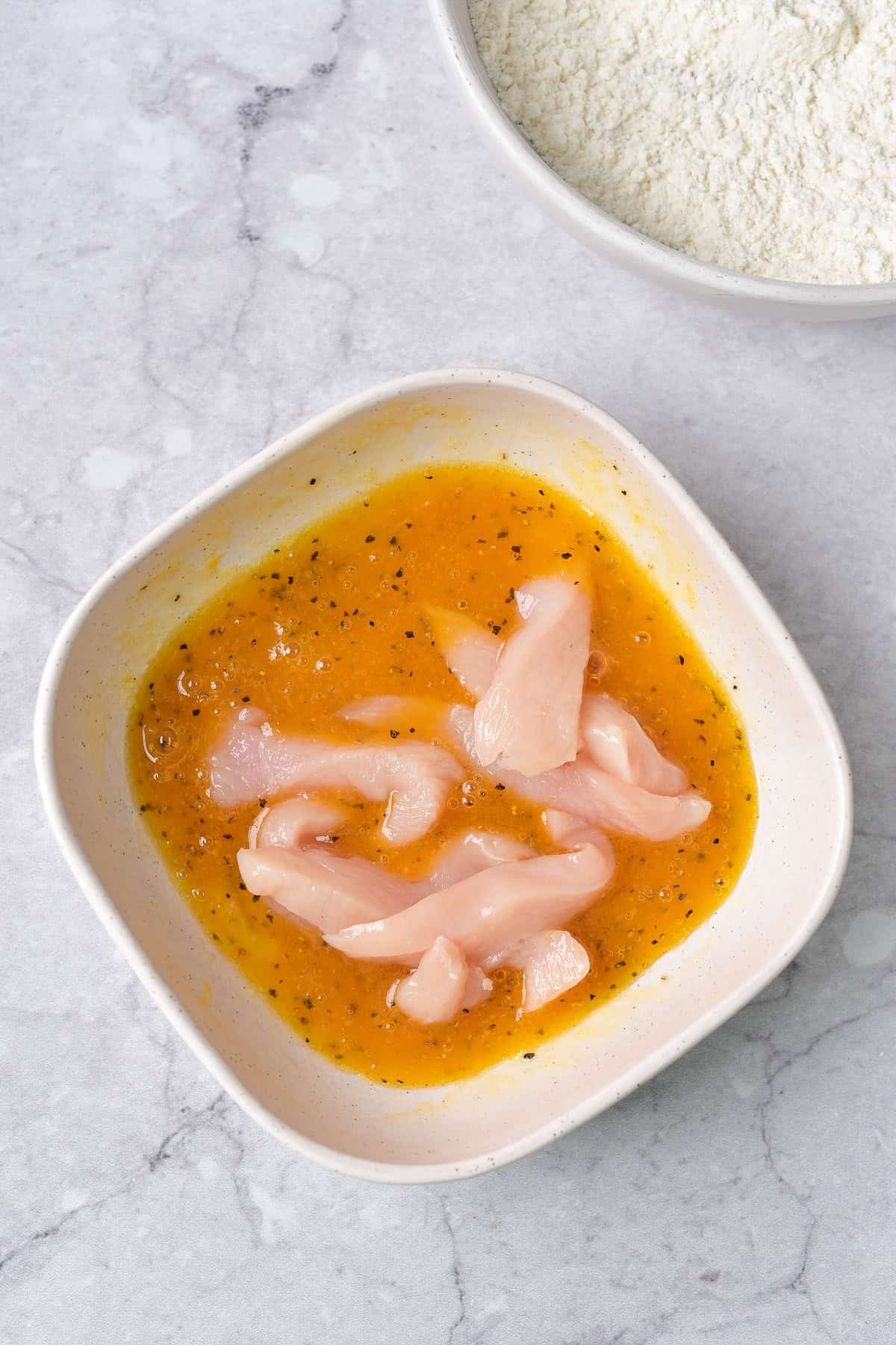 Strips of chicken in the wet mixture.