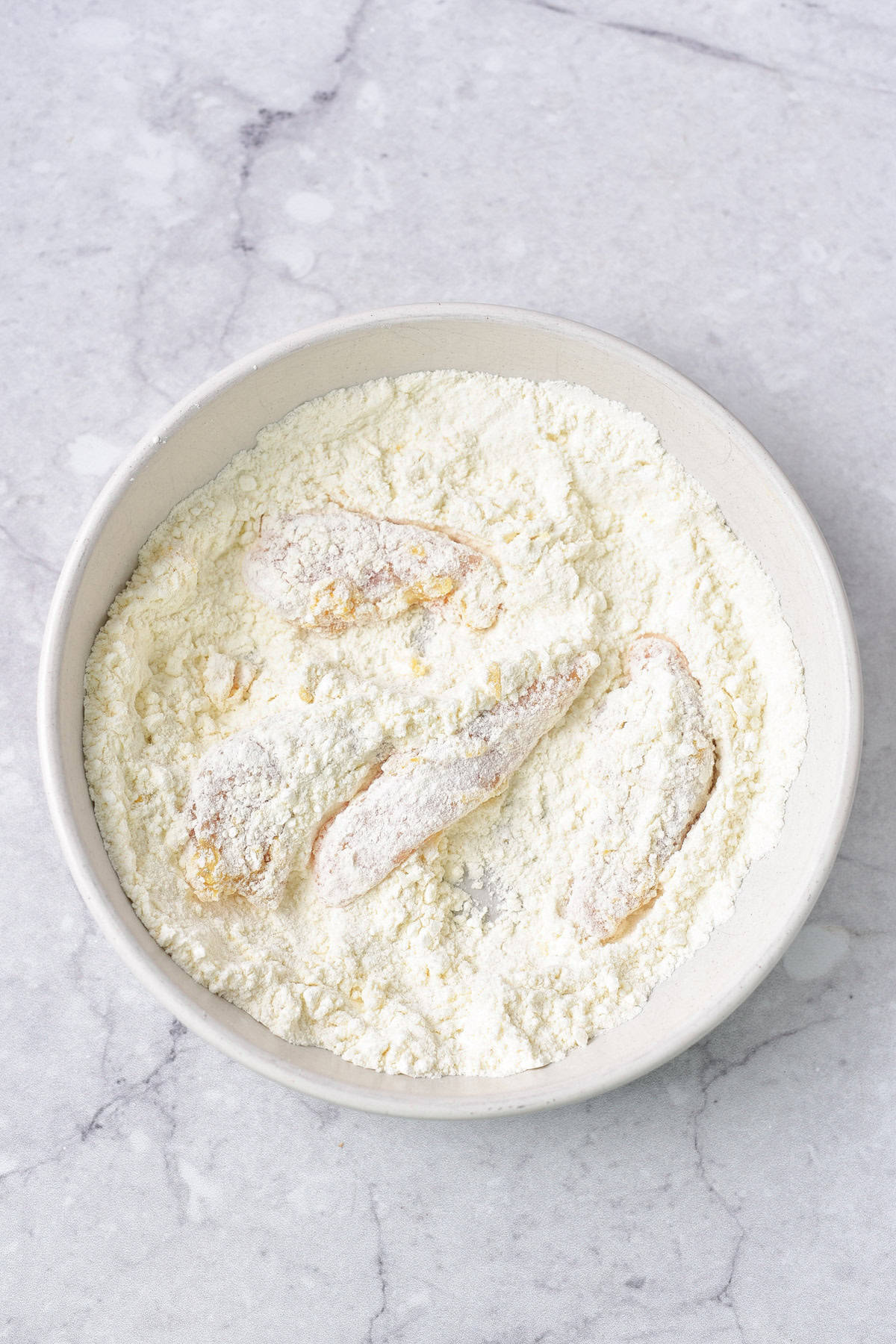 Dredging the chicken in the flour.