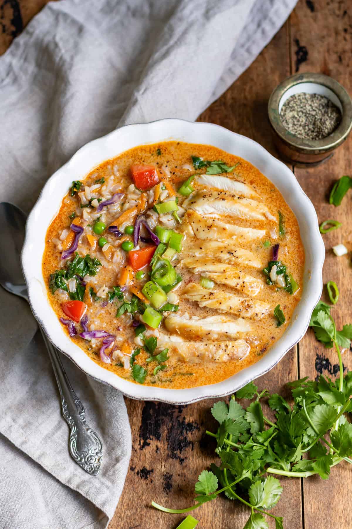 Looking down at a table with a bowl of Thai Chicken Soup with rice.