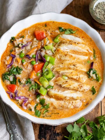 Looking down at a table with a bowl of Thai Chicken Soup with rice.