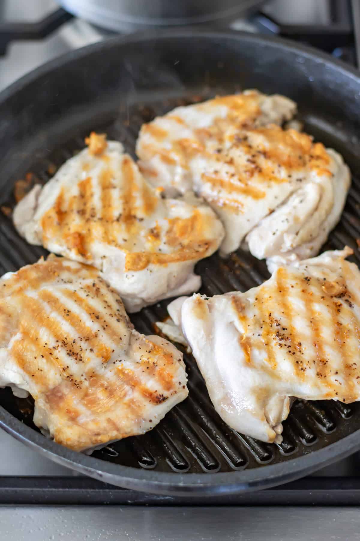 Grilling chicken thighs on a grill pan.