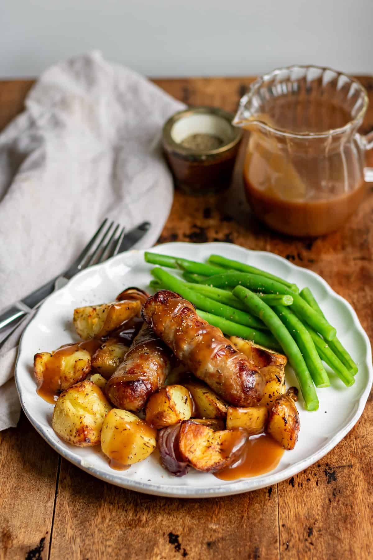 Plate of potato sausage bake with green beans and gravy.