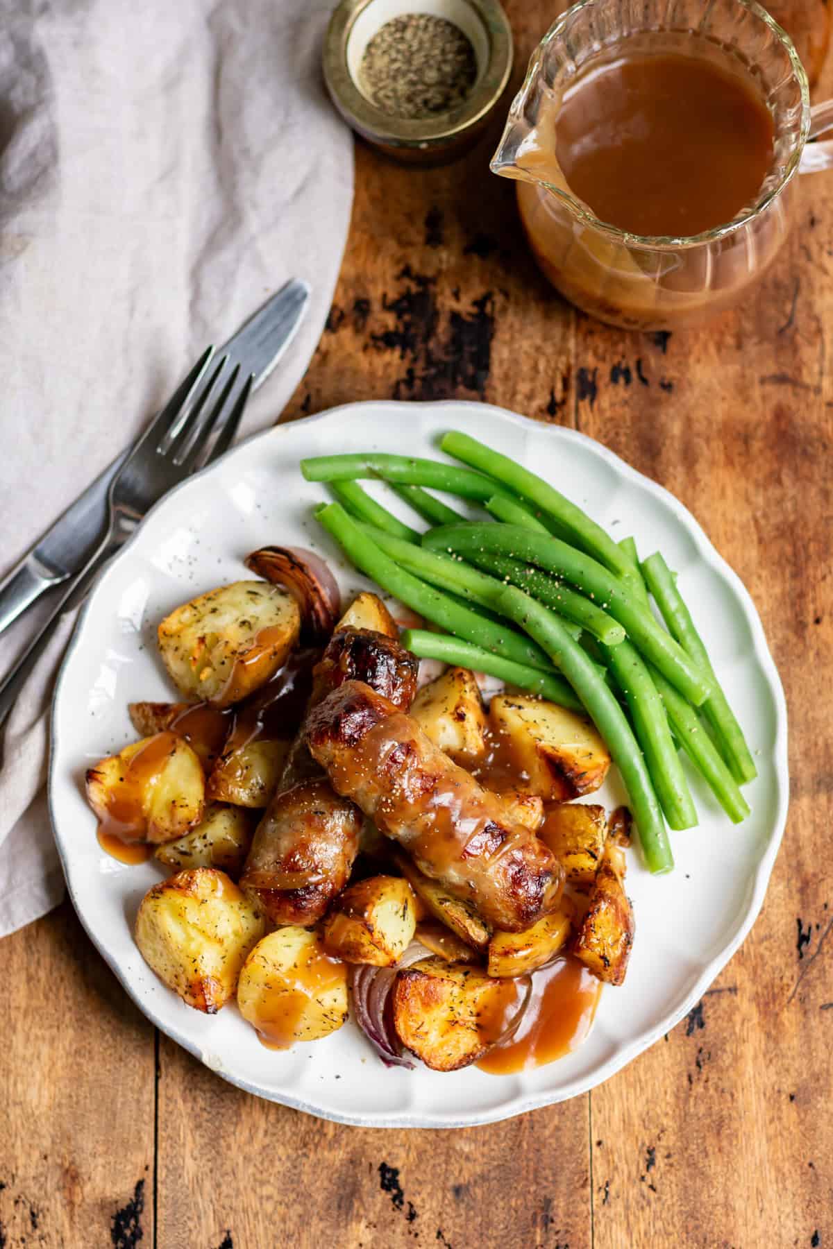 Looking down at a plate with green beans, and potato sausage bake, with gravy.