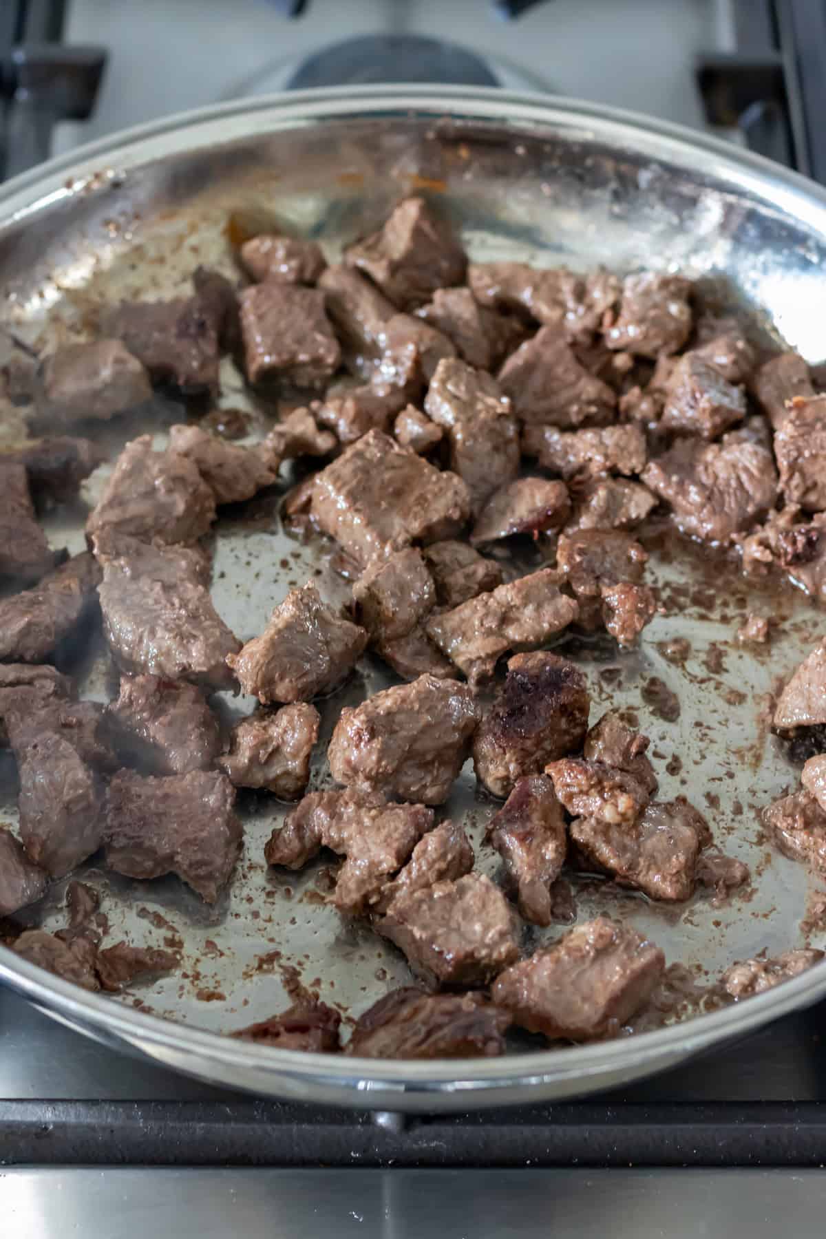 Searing the beef in a skillet.