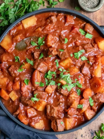 A serving dish of easy crock pot beef stew on a wooden table.