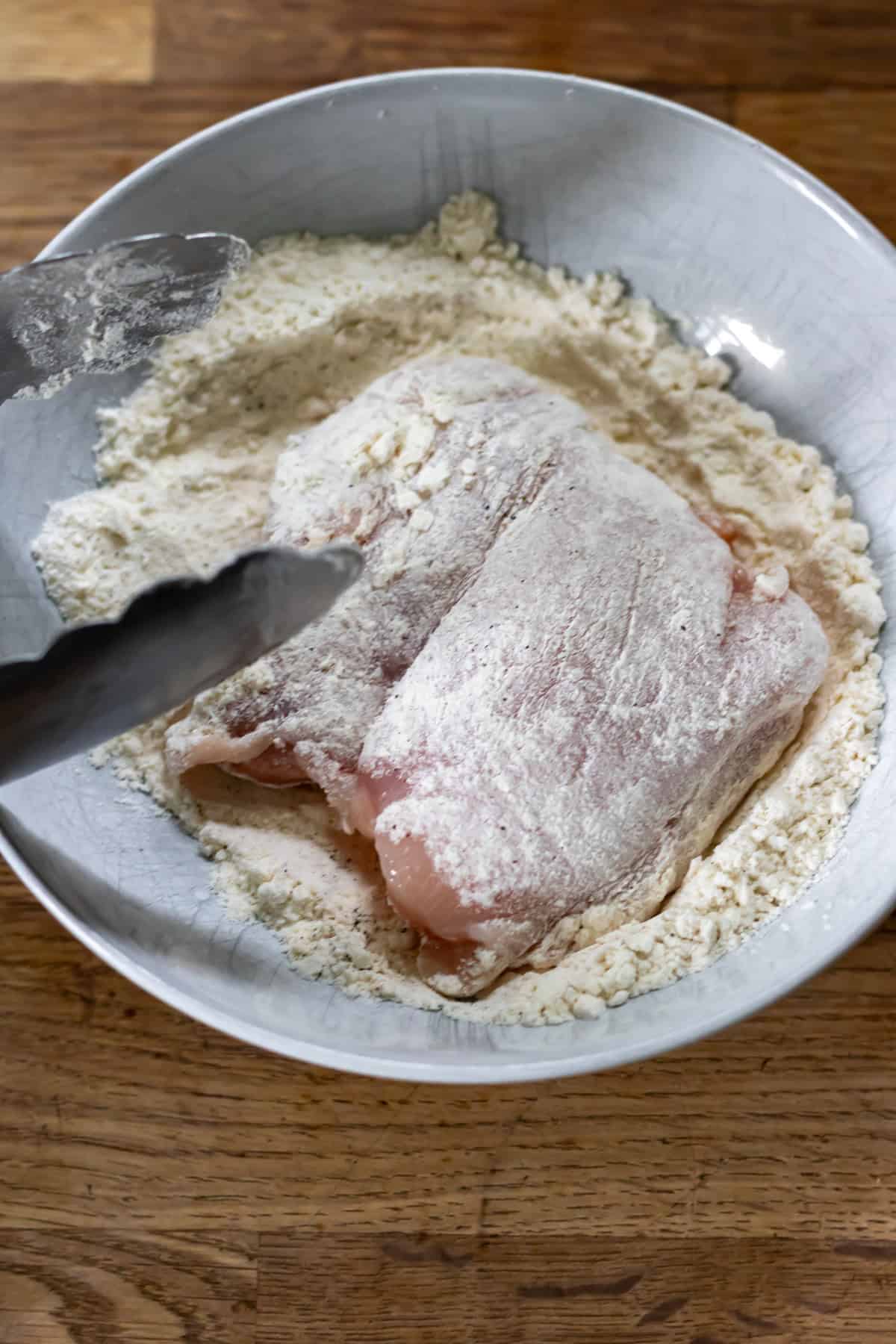Coating the chicken in flour.