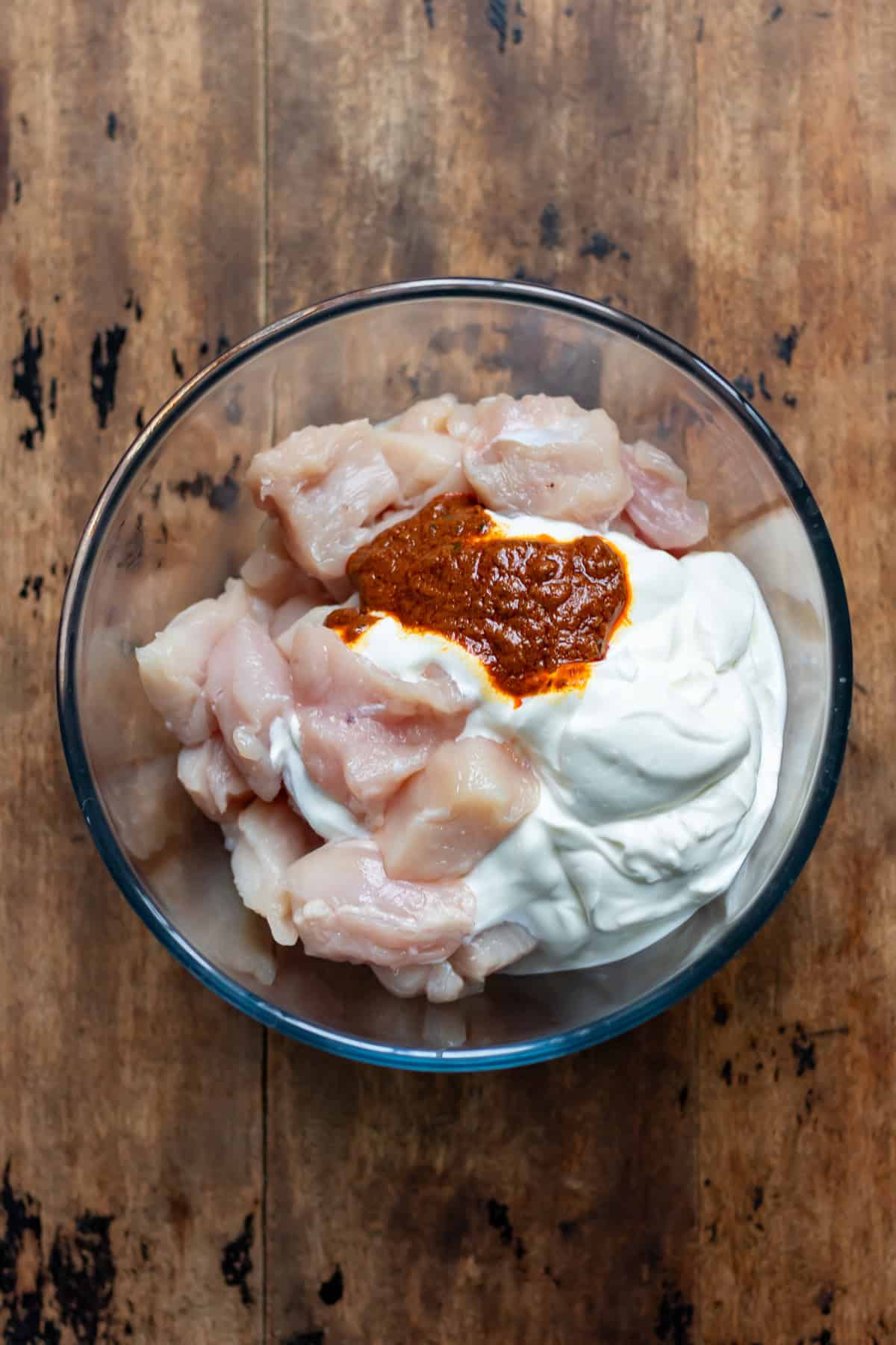Chicken, yogurt and tikka paste in a bowl.