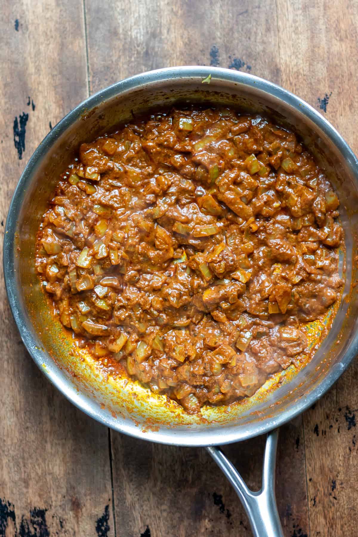 Skillet frying onion and tikka paste.