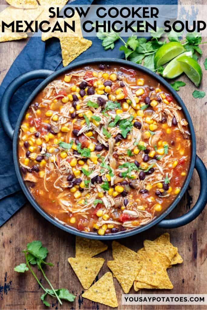 Serving dish of soup on a table surrounded by sliced limes and tortilla chips, with text: Slow Cooker Mexican Chicken Soup.
