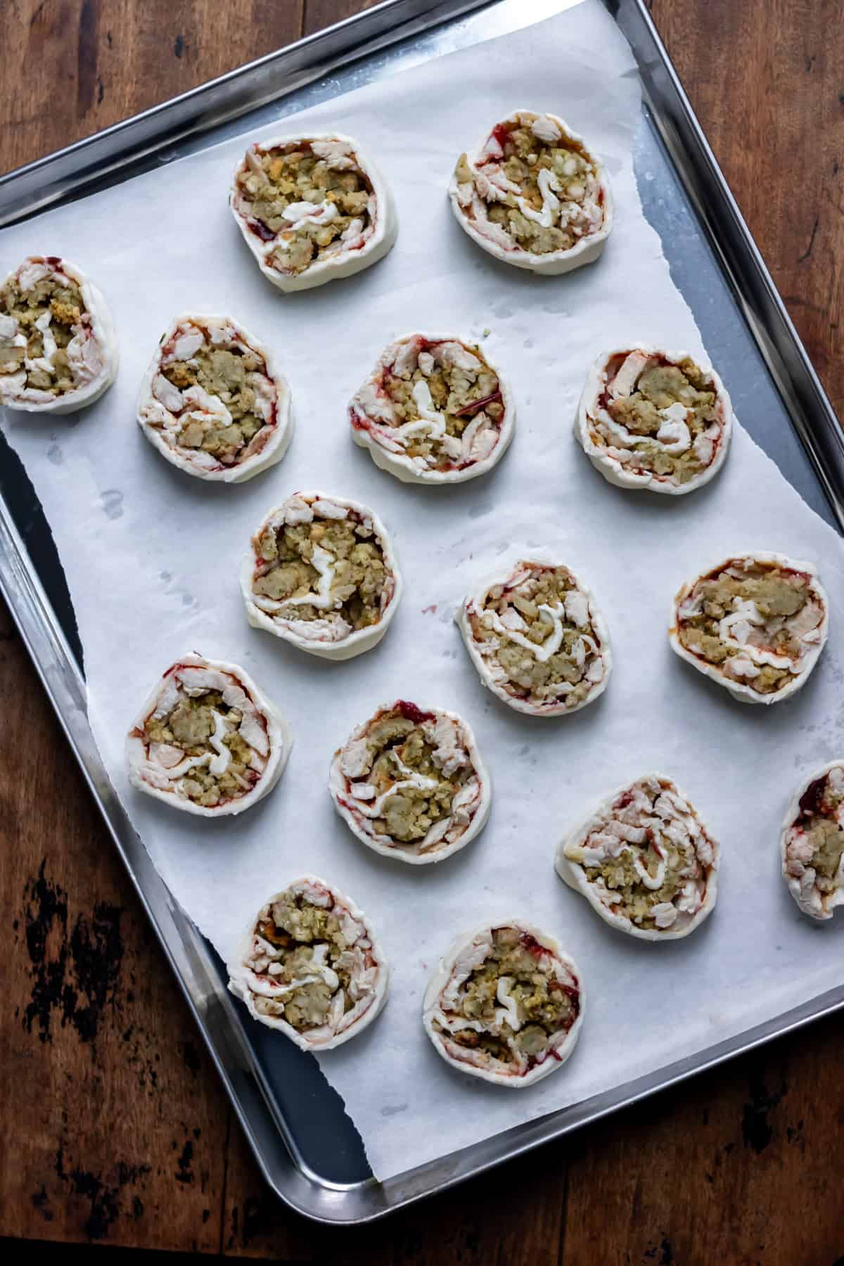 Unbaked turkey pinwheels placed onto a baking sheet lined with parchment paper.