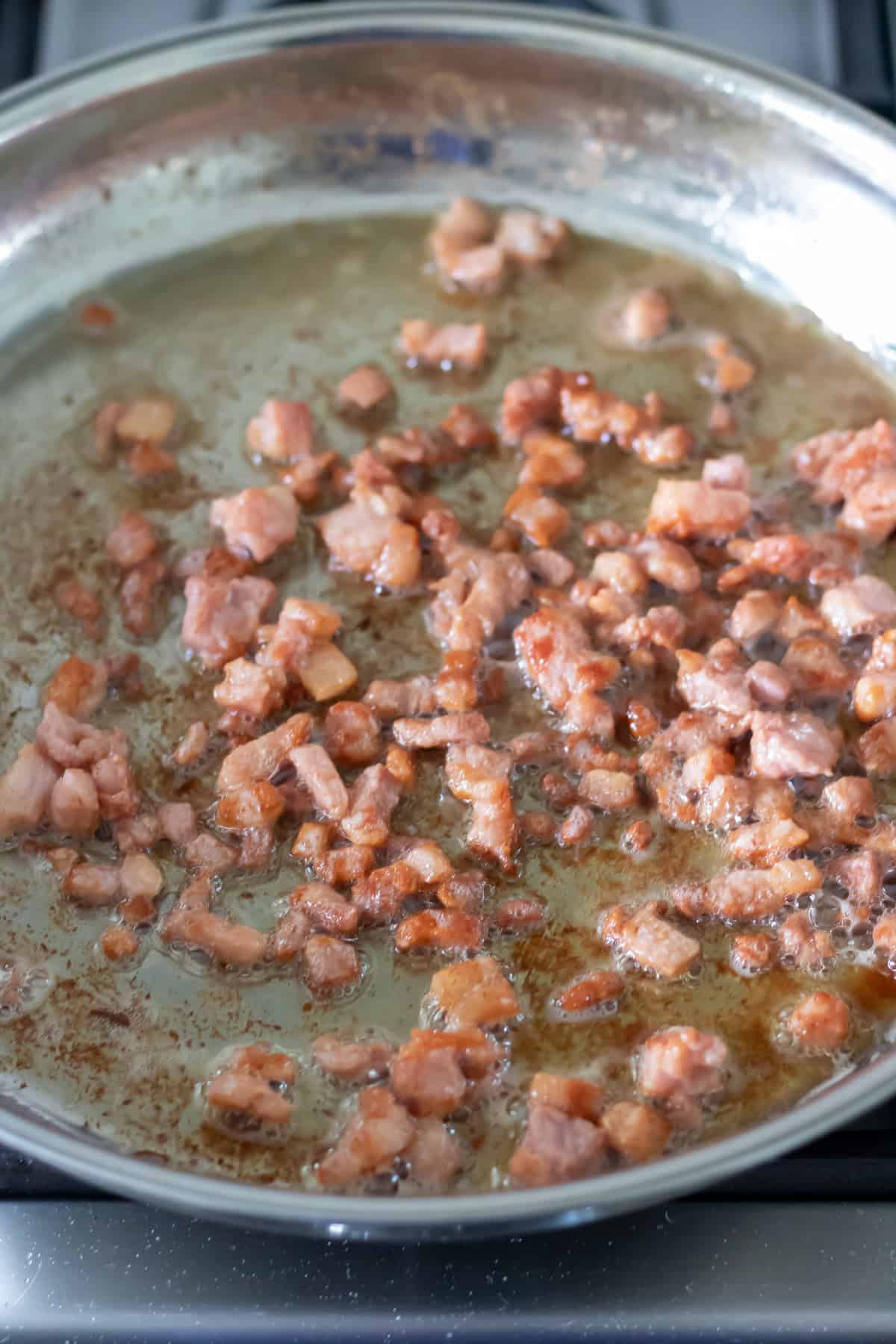 Pan frying the bacon lardons.