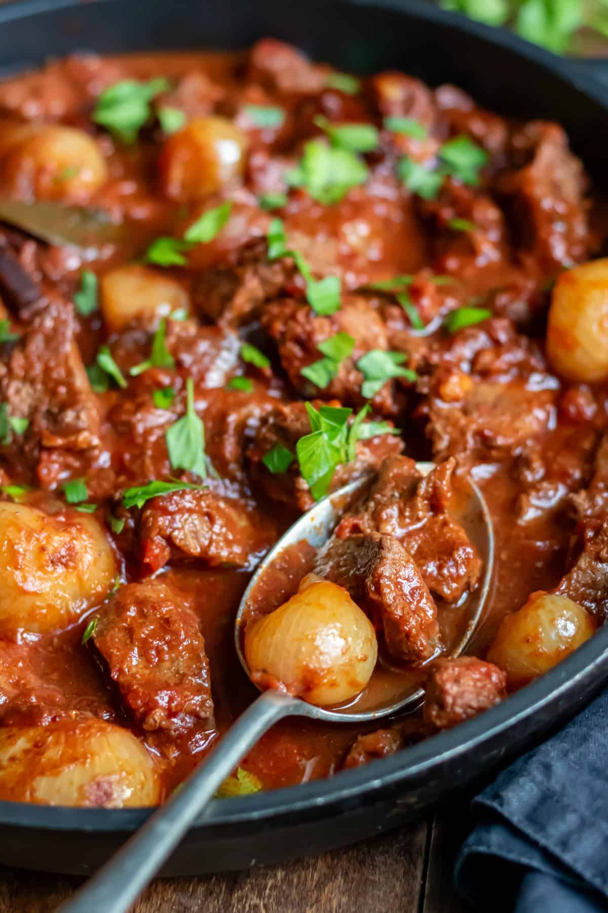 Spoon in a dish of slow cooker Greek stifado.