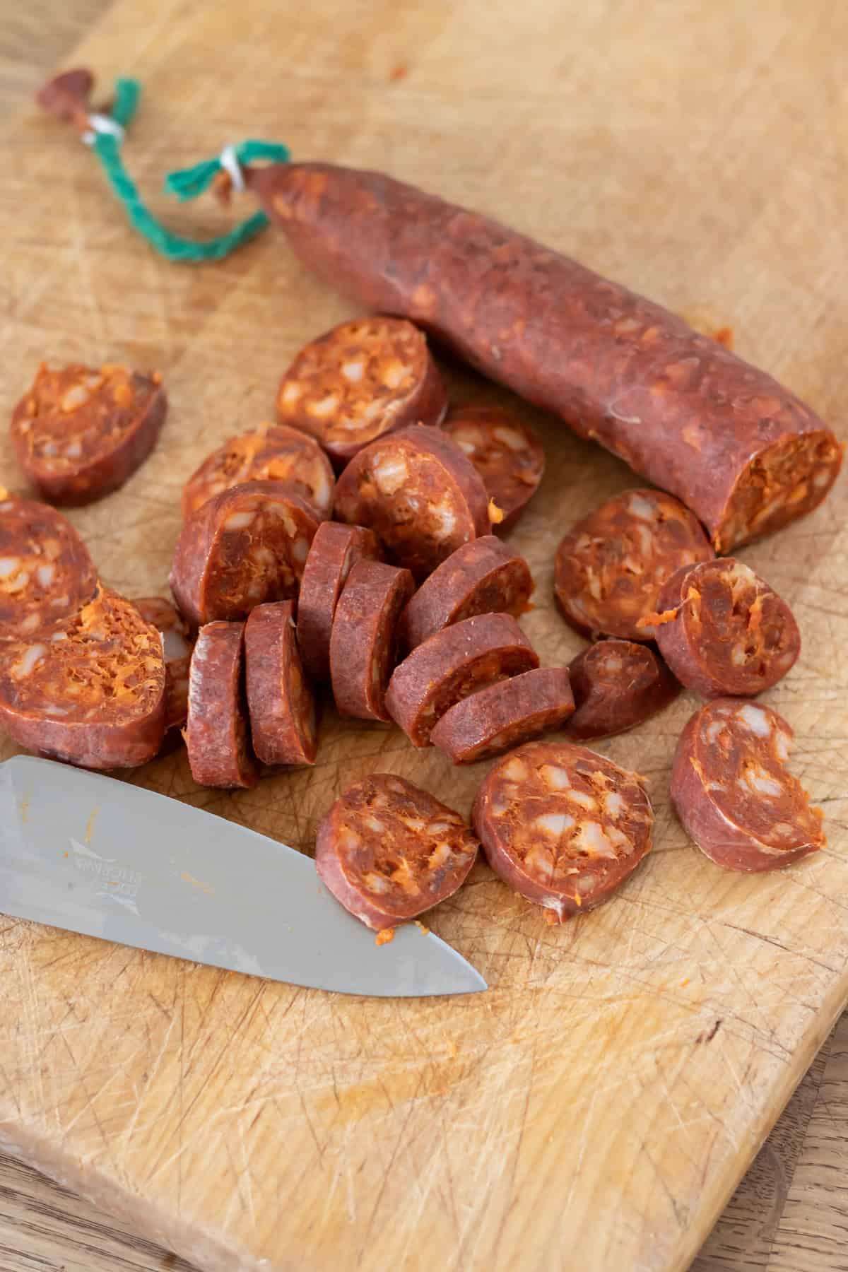 Slicing the chorizo on a cutting board.