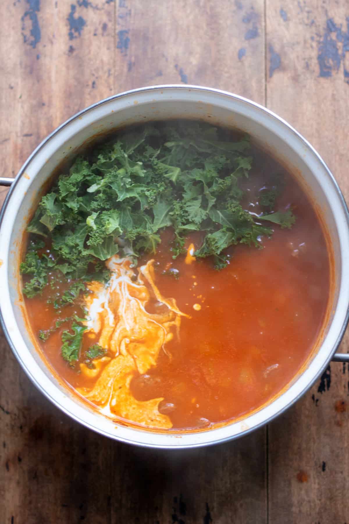 Adding the cream and kale to the pot.
