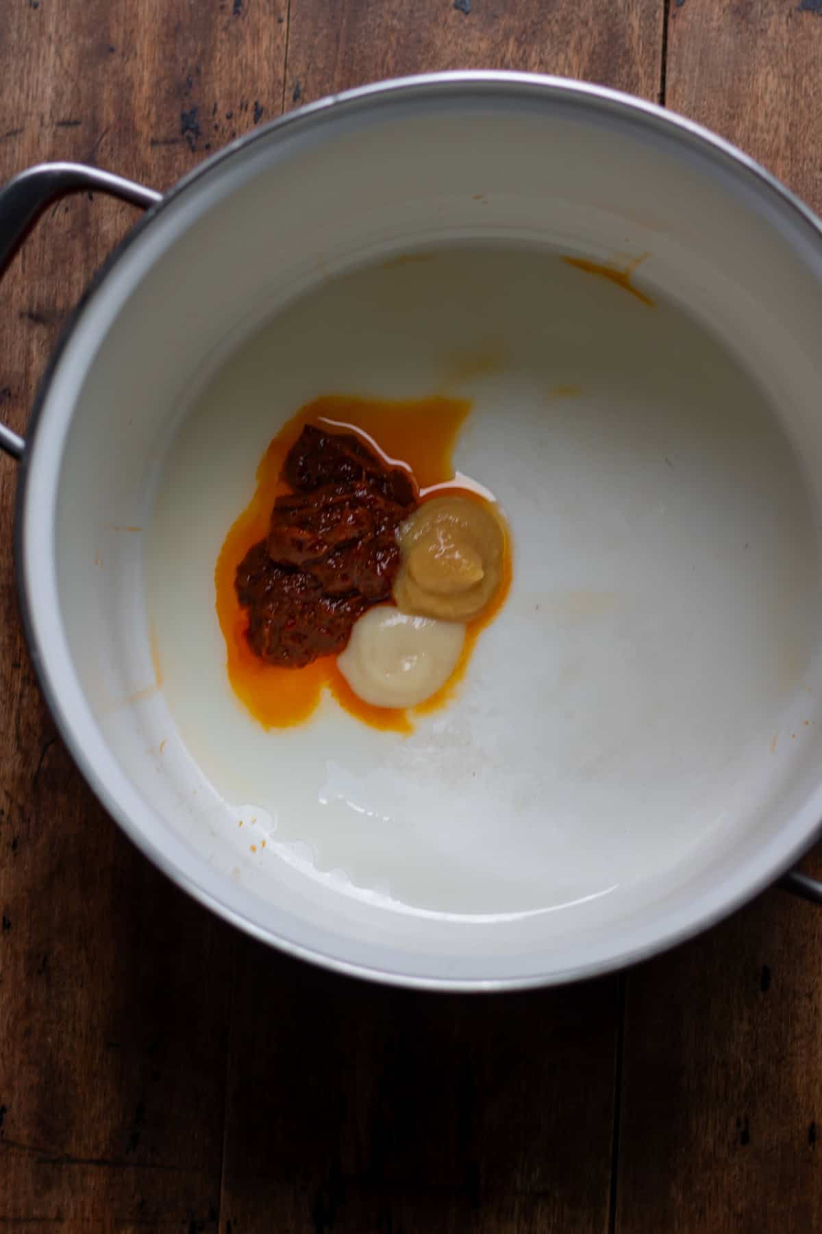 Thai red curry paste, garlic paste and ginger paste in a soup pot.