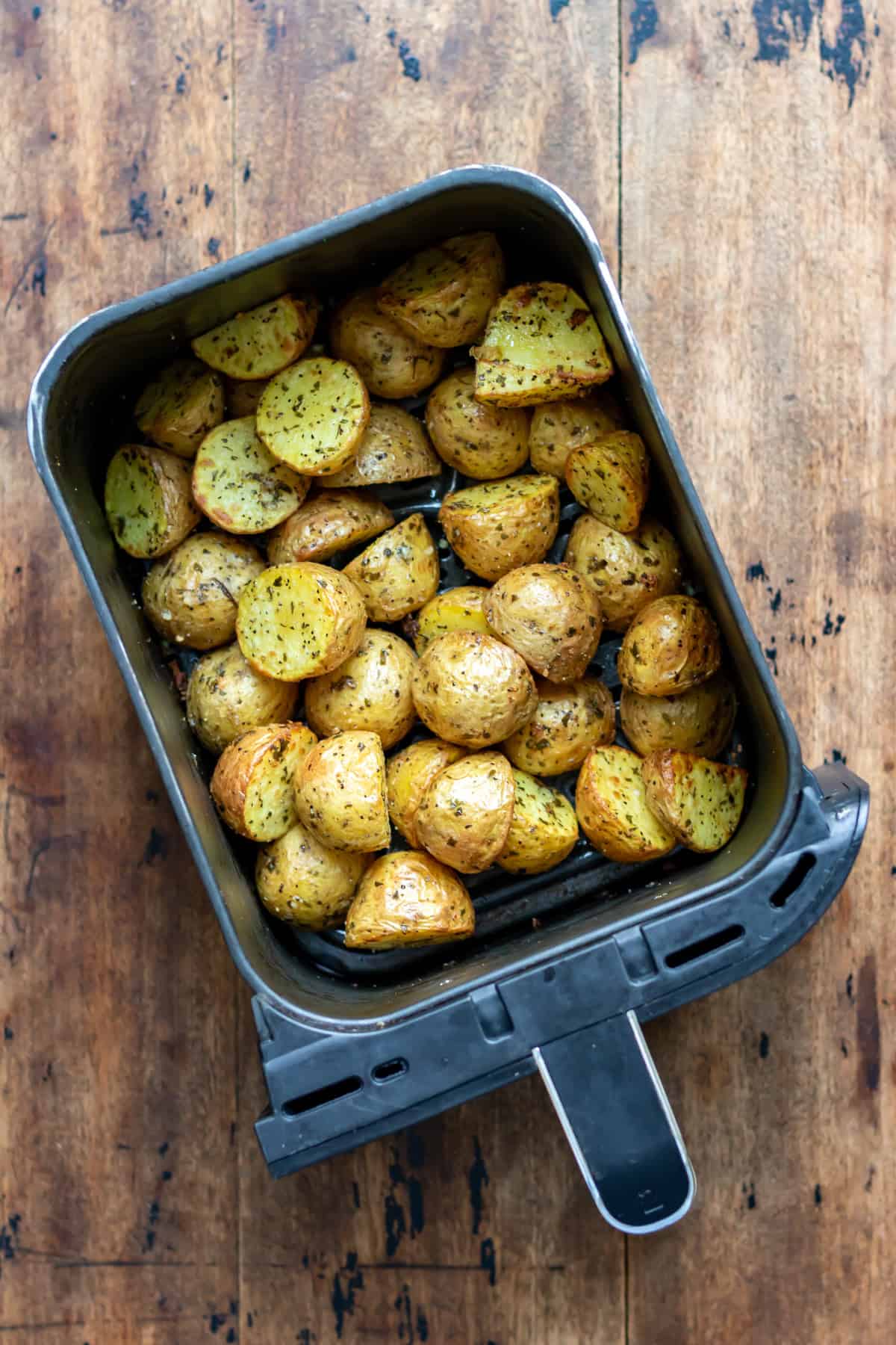 An air fryer basket of cooked garlic baby potatoes.