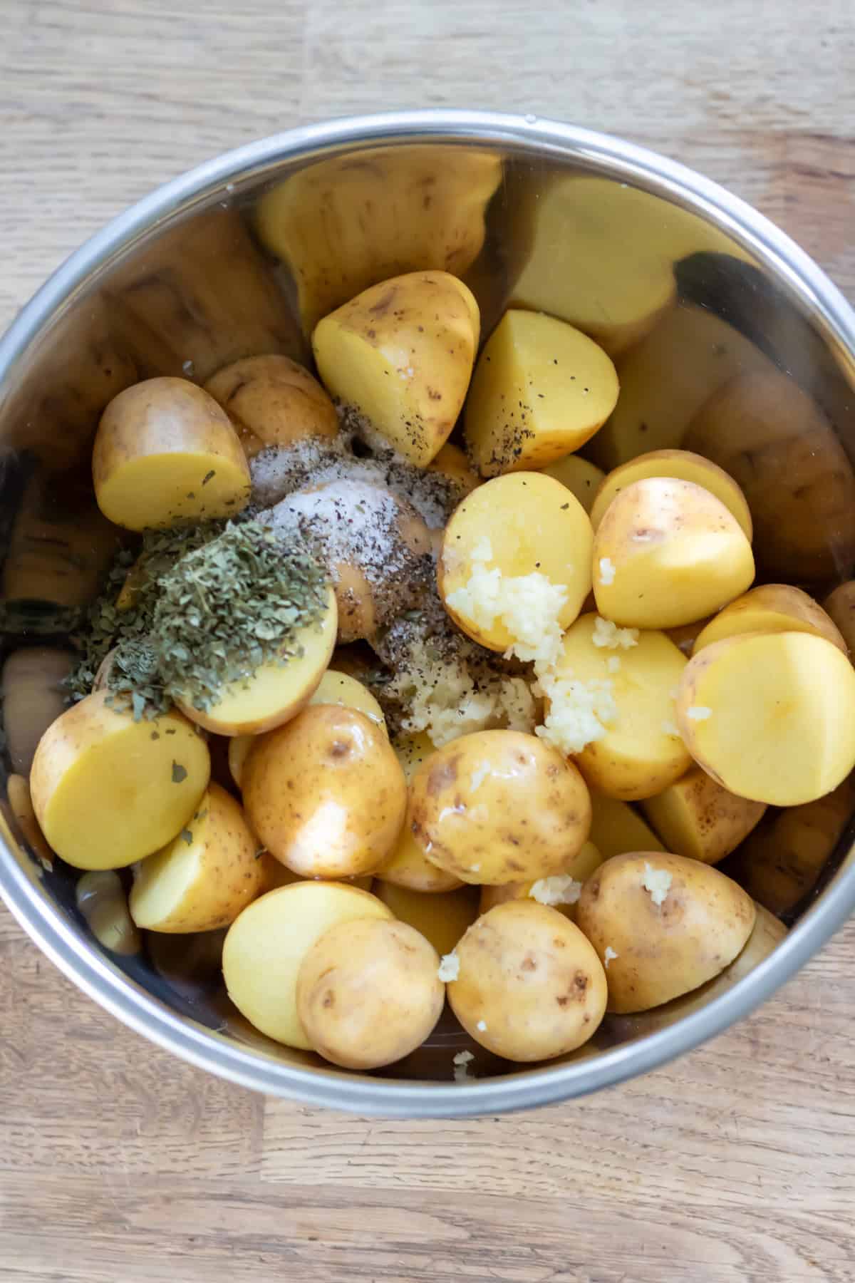 Baby potatoes in a bowl along with the oil, salt, pepper, garlic and dried parsley.