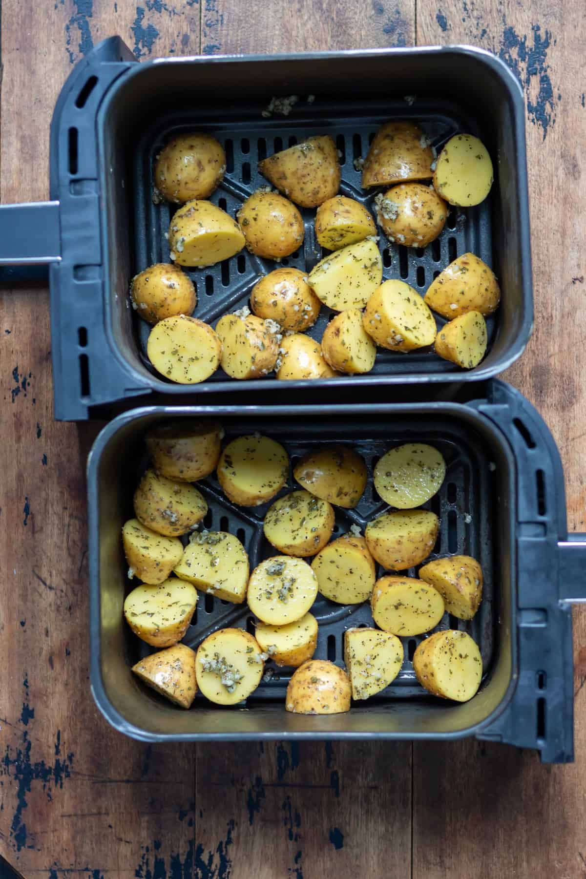 Coated potatoes in two air fryer baskets.
