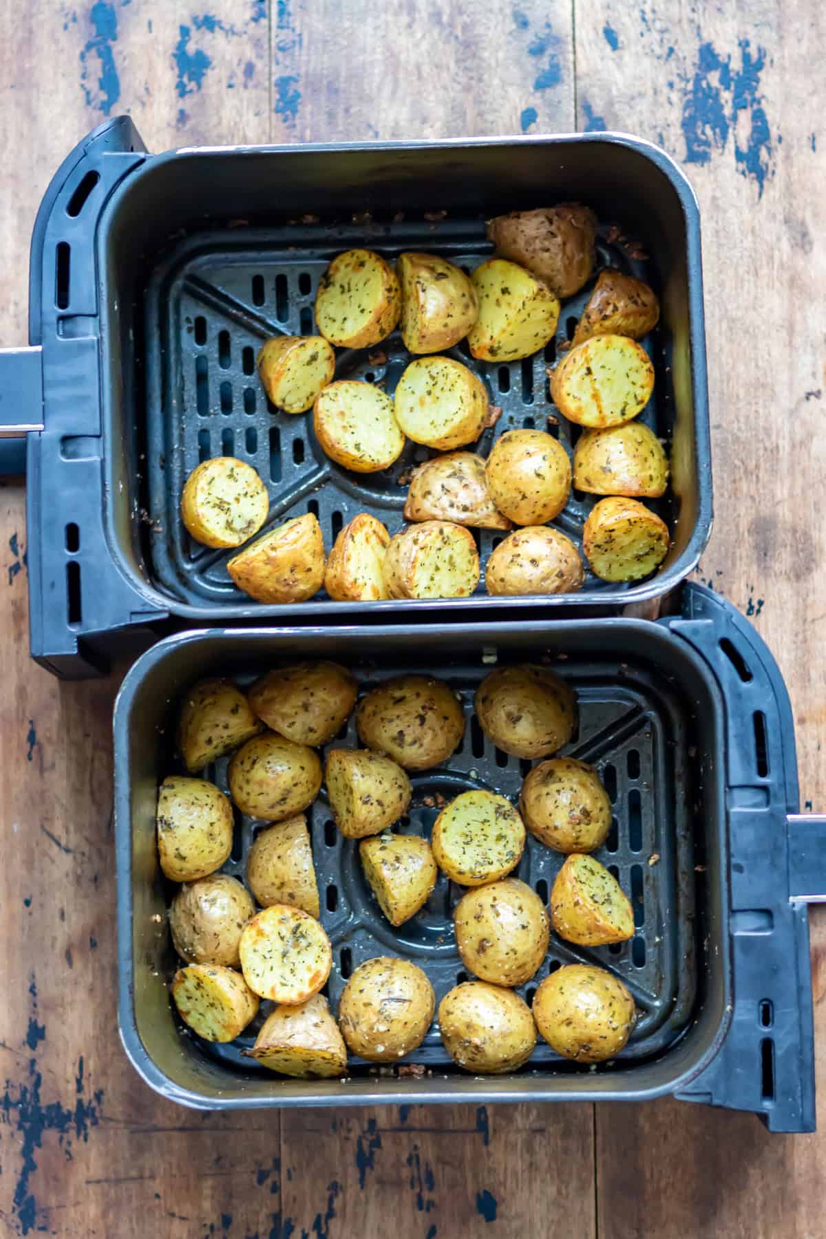 Roasted air fryer garlic baby potatoes in two air fryer baskets.