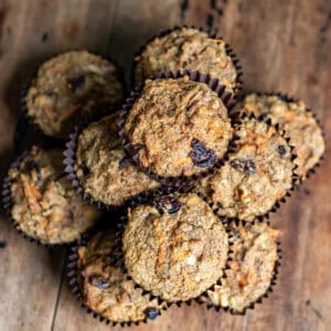 Looking down at a stack of carrot cake high fiber muffins on a wooden table.