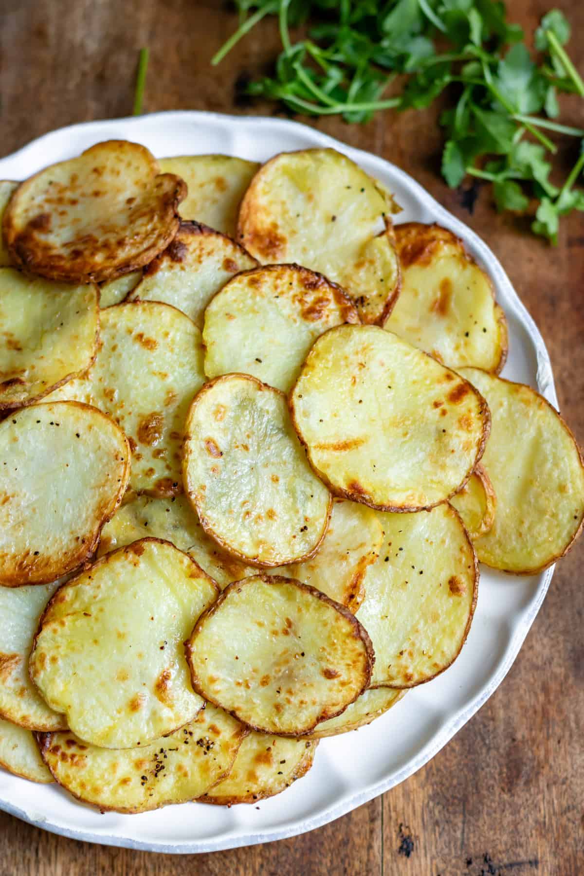 Looking down at a table with a plate of air fried sliced potatoes.