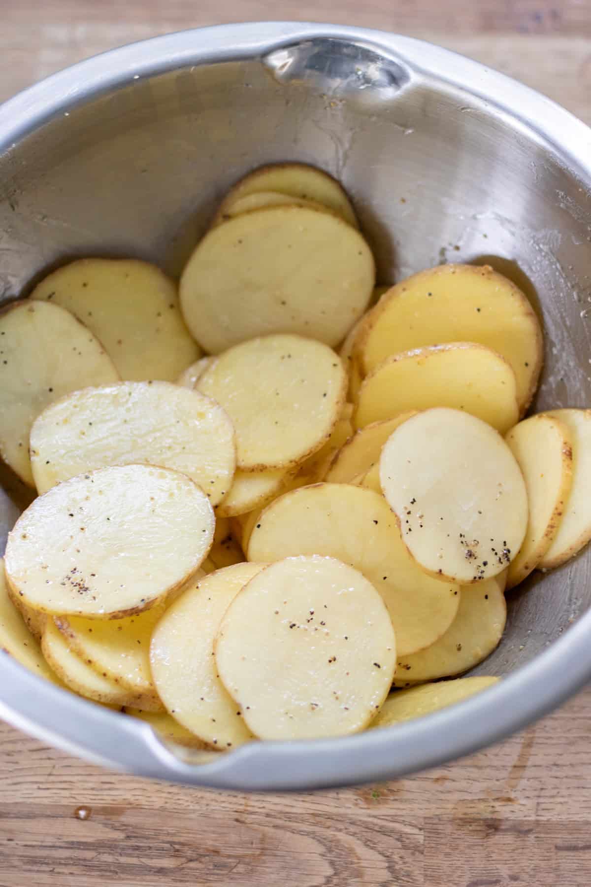 Coated potato slices in a bowl.