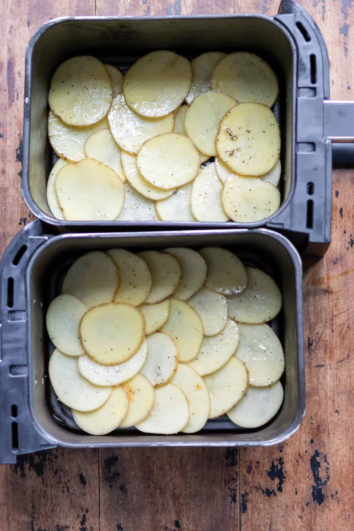 Coated sliced potatoes in the baskets of an air fryer.