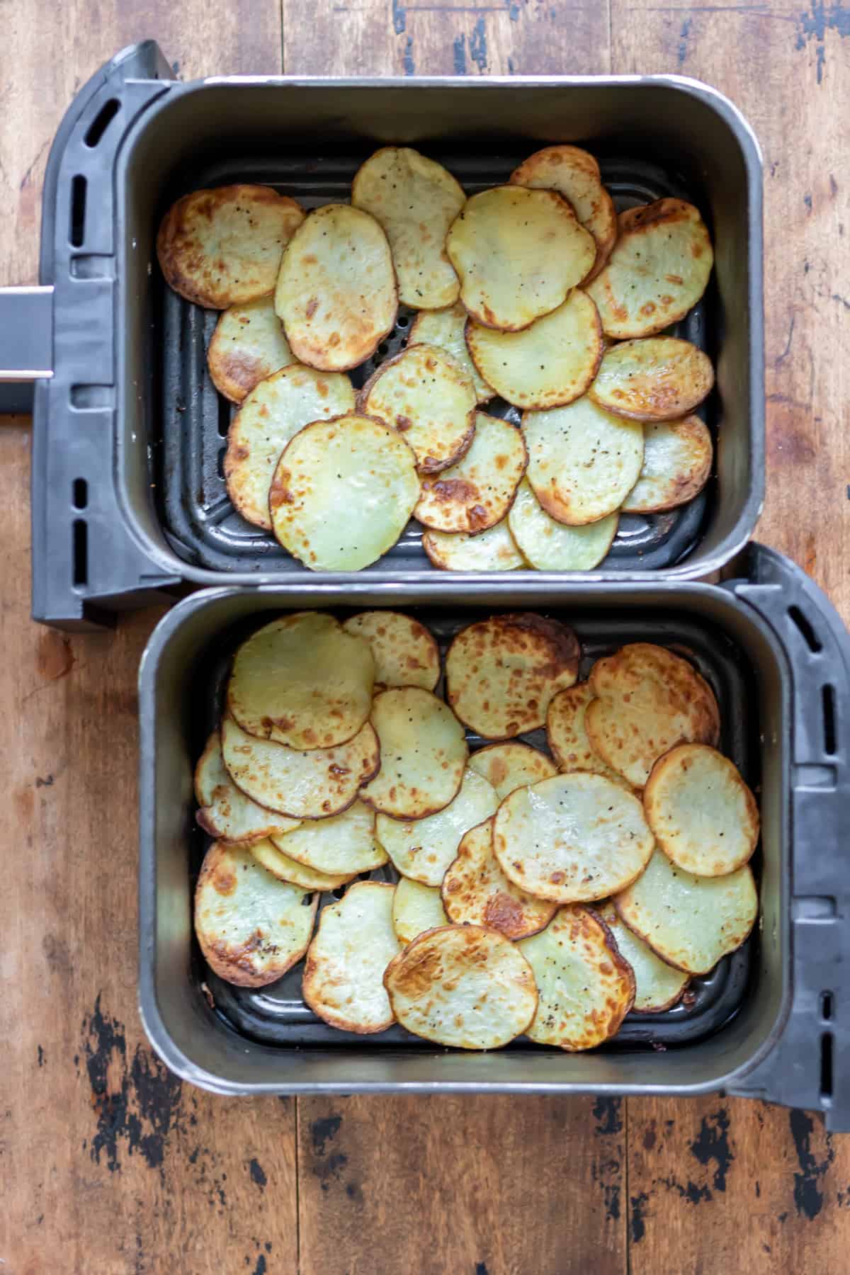 Air Fried crispy sliced potatoes in the baskets of the air fryer.