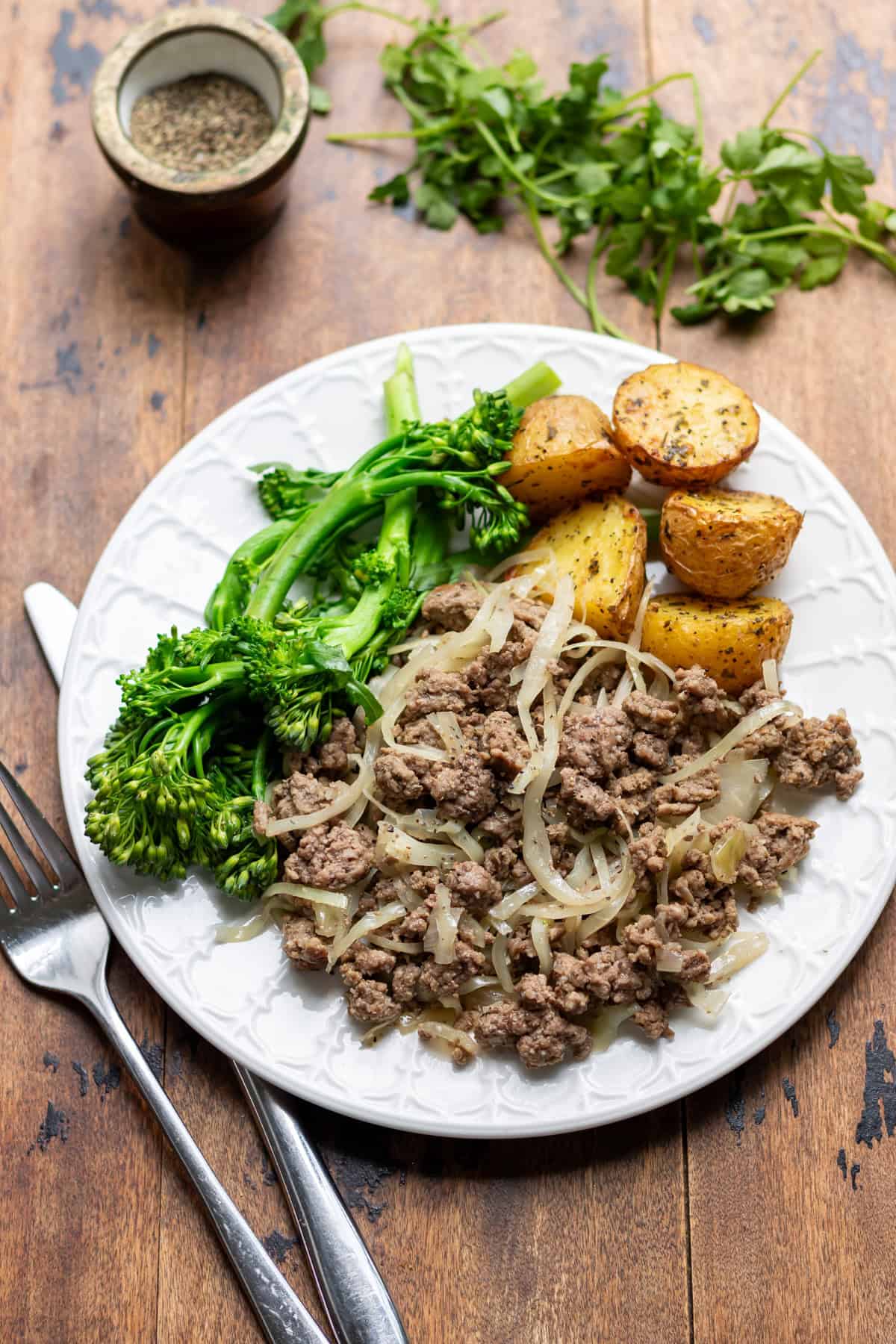 Plate of ground beef and cabbage skillet with roasted baby potatoes and broccoli.