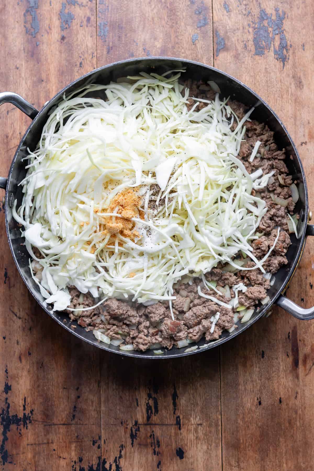 Cabbage and seasonings added to the pan of ground beef.