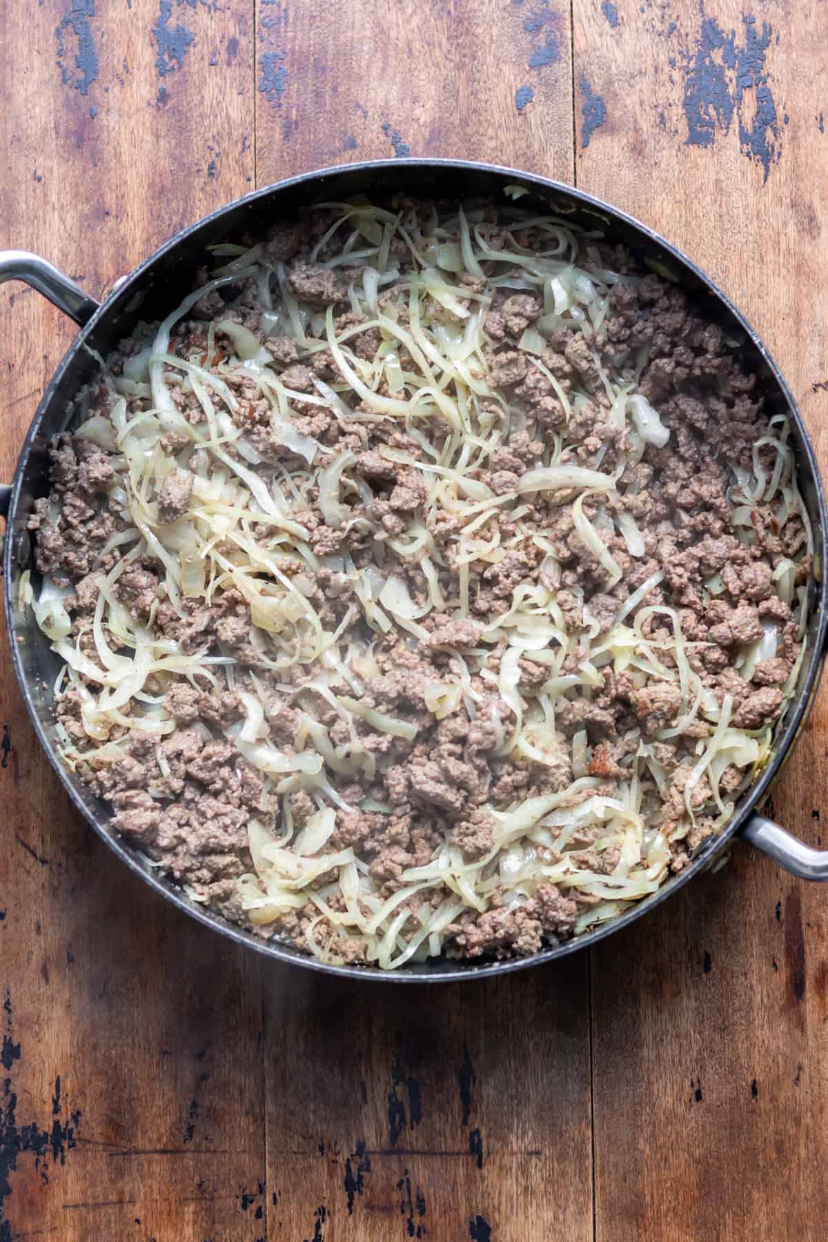 Cooked ground beef and cabbage in a skillet.