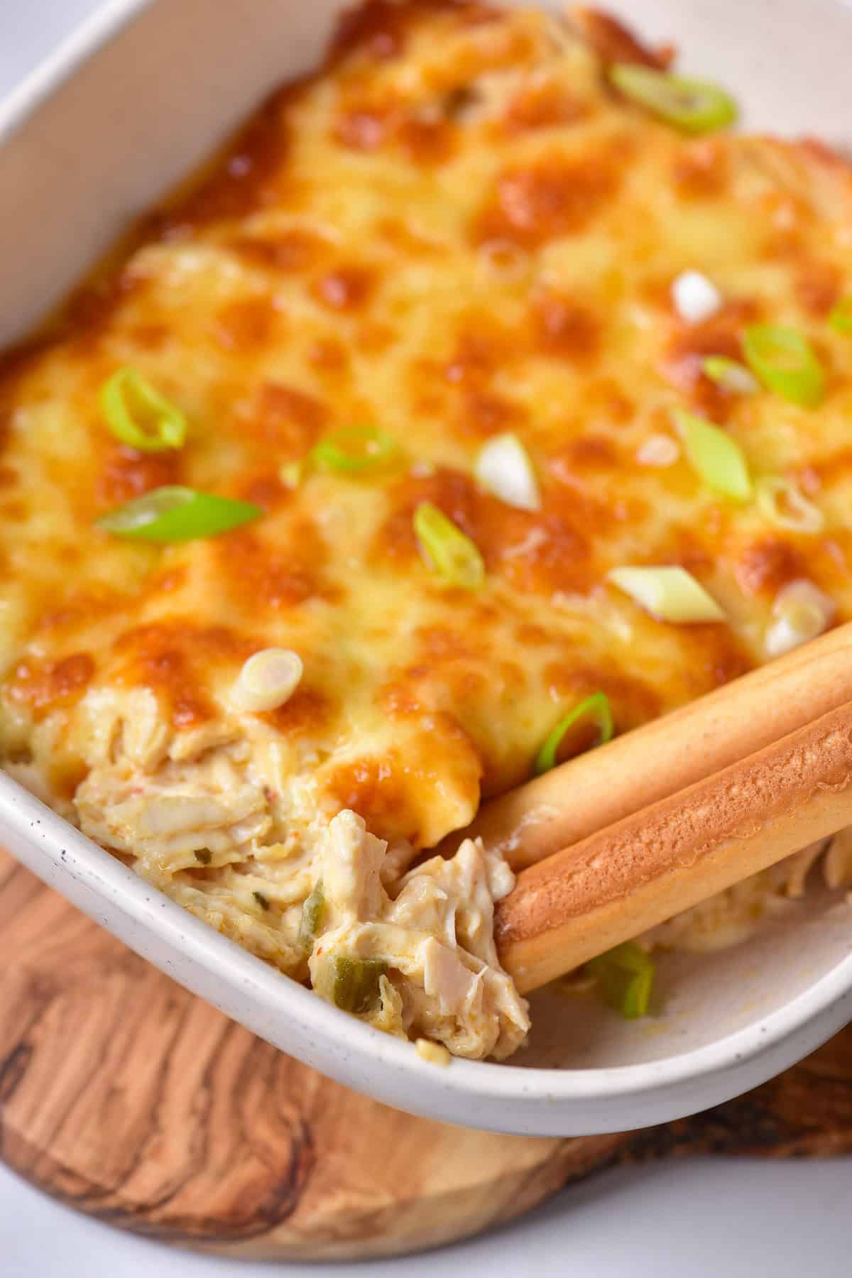 A baking dish of buffalo ranch chicken dip on a table.