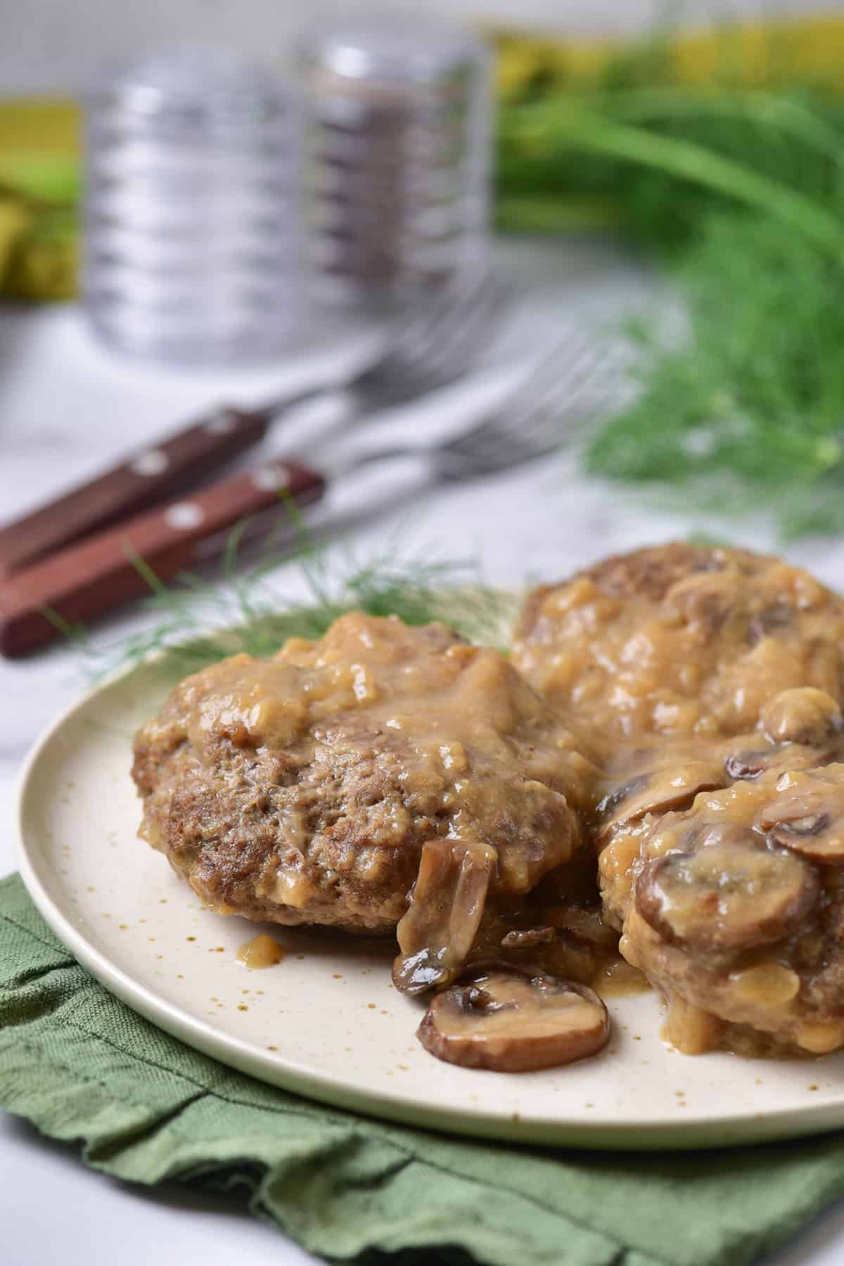 Side view of a plate of Salisbury steaks with mushroom gravy.