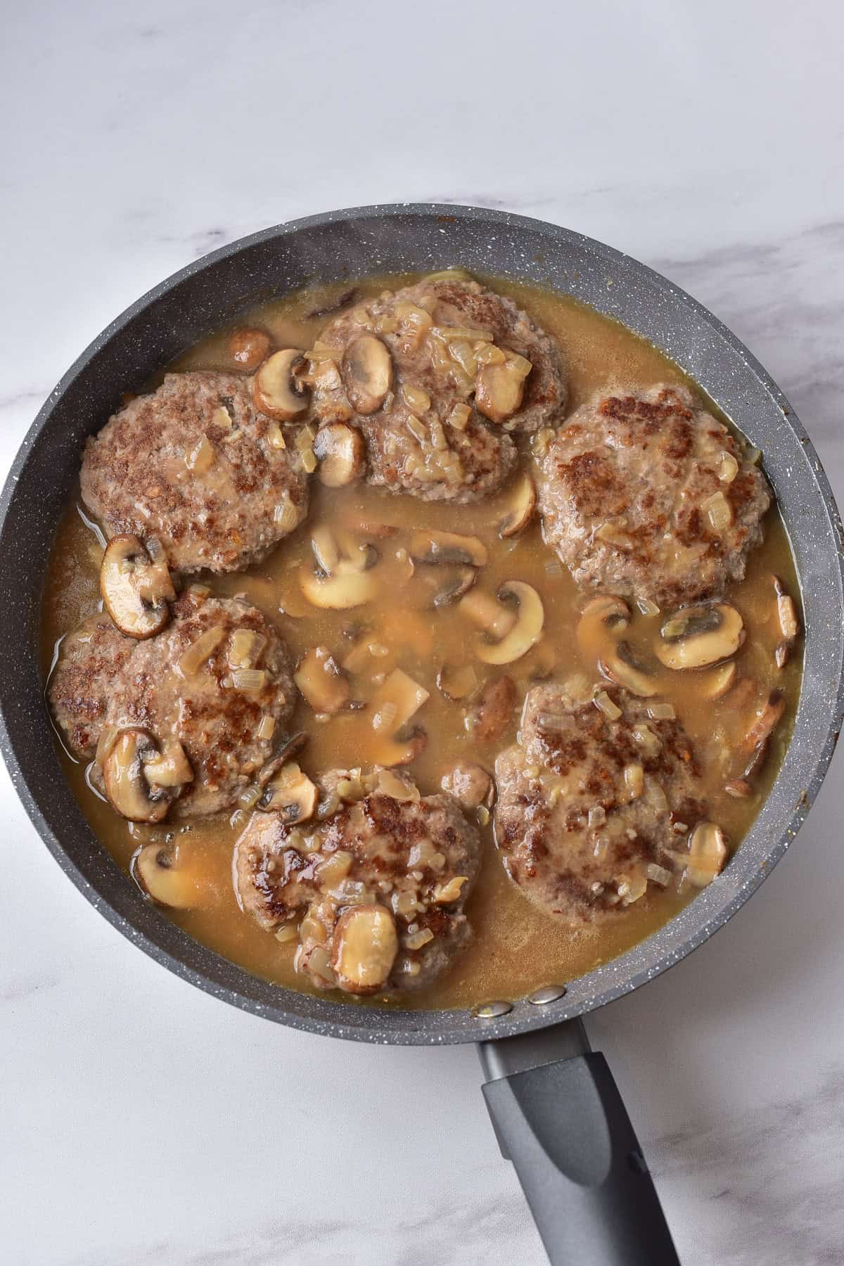 Simmering the salisbury steaks in the mushroom gravy.