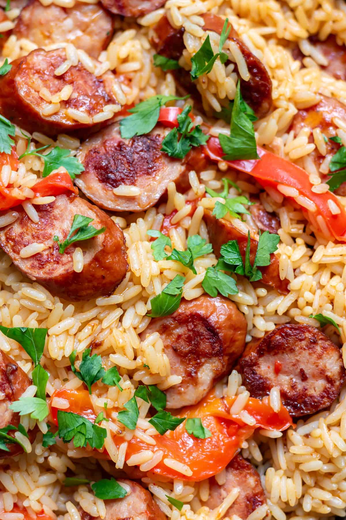 Pan of kielbasa sausage rice skillet meal with red bell peppers and parsley.