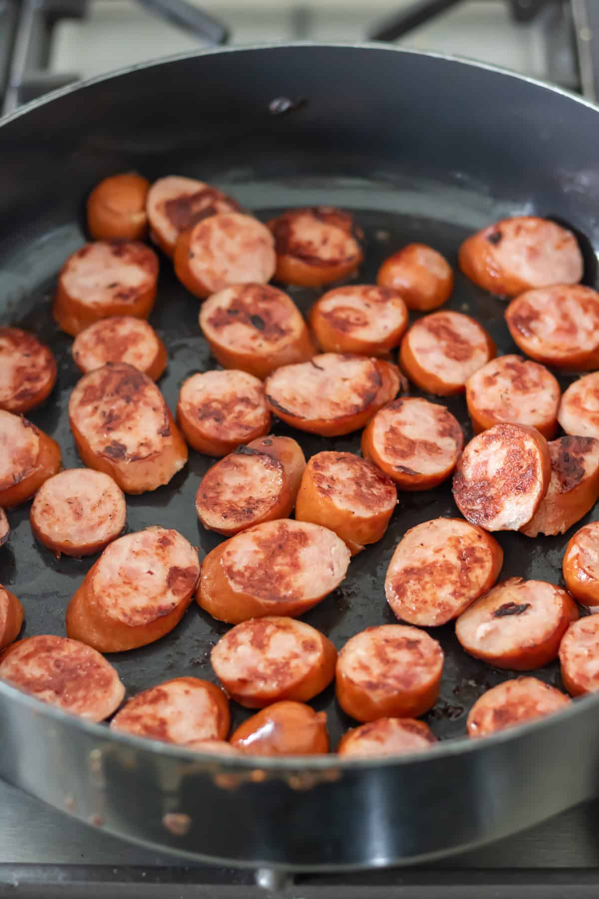 Frying kielbasa sausage in a pan.