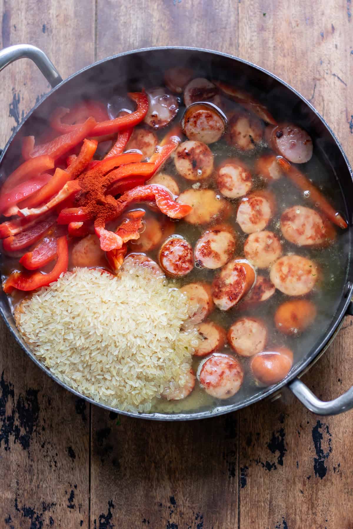 Adding the stock, rice, bell peppers and smoked paprika.